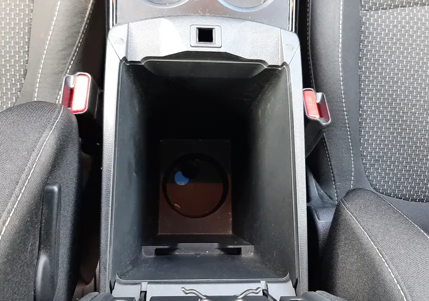 Vue plongeante sur la console centrale noire ouverte du Renault Kadjar gris, avec porte-gobelets et sièges tissu gris.