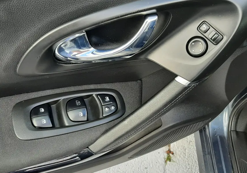 Poignée intérieure chromée et commandes électriques sur la porte côté conducteur du Renault Kadjar gris 2018.