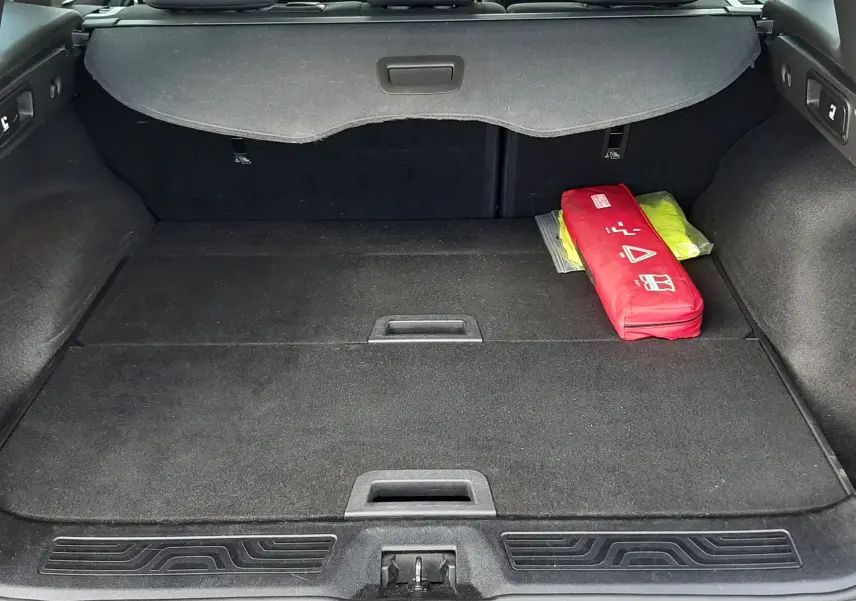 Coffre ouvert du Renault Kadjar gris 2018 vu de l'arrière, avec cache-bagages et trousse de secours rouge à droite.
