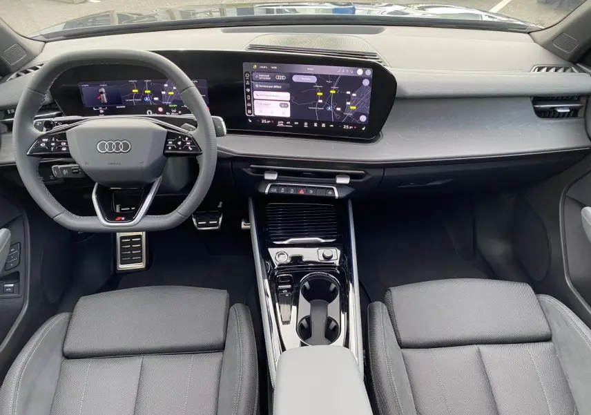 Vue intérieure avant de l'Audi Q3 2025, tableau de bord moderne noir avec écran tactile et volant sport multifonction.
