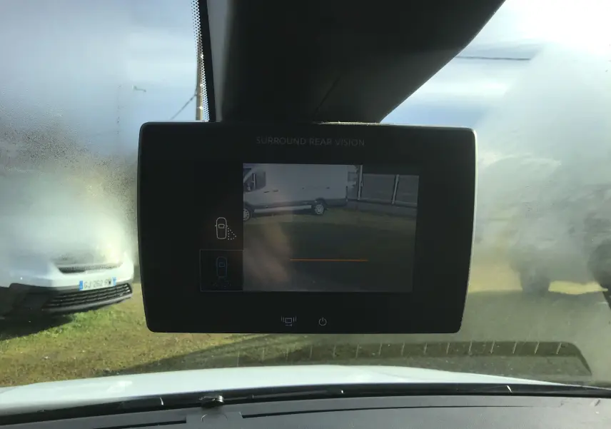 Vue intérieure centrée sur l'écran de caméra de recul du Citroën Berlingo blanc, avec pare-brise partiellement embué.