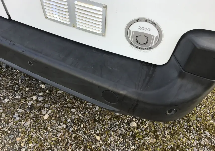 Gros plan sur le pare-chocs arrière noir d’un Citroën Berlingo blanc avec autocollant "International Van of the Year 2019".