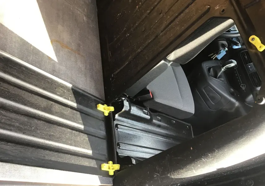 Vue intérieure en plongée du compartiment de chargement noir et siège avant gris du Citroën Berlingo blanc de 2019.