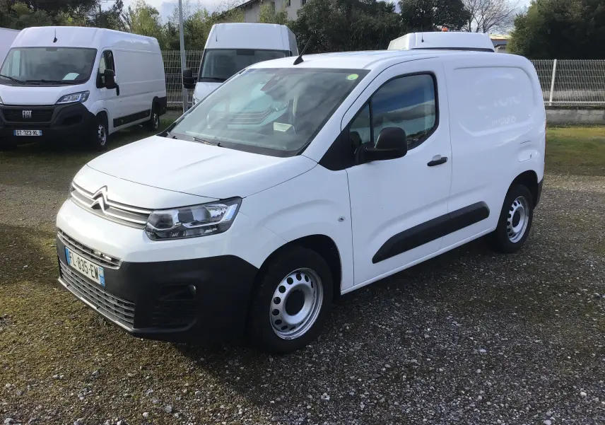 Citroën Berlingo blanc en vue 3/4 avant droit, fourgonnette utilitaire avec protections noires sur les portières.
