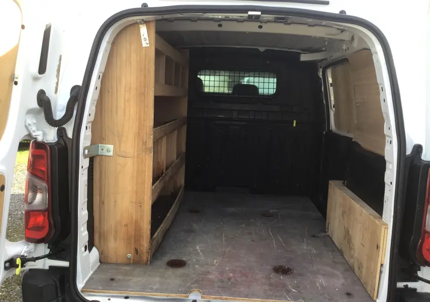 Vue arrière intérieure du Citroën Berlingo blanc 2019 avec aménagements bois pour rangement et protection des parois.