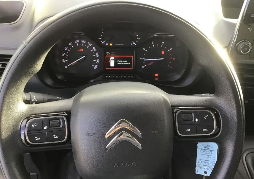 Vue rapprochée du volant noir du Citroën Berlingo blanc 2019 avec commandes intégrées et tableau de bord numérique.