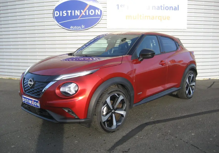 Nissan Juke 1.6 Hybrid 143 Tekna rouge en 3/4 avant droit avec jantes bi-ton et calandre noire brillante.