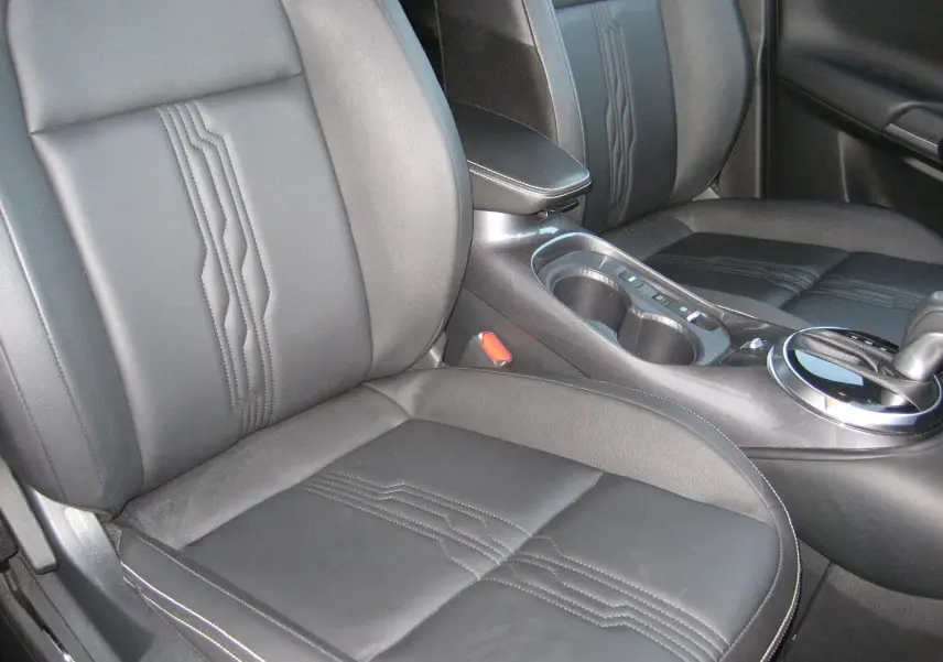 Gros plan sur les sièges avant en cuir noir et la console centrale du Nissan Juke 1.6 Hybrid 143 Tekna 2024.