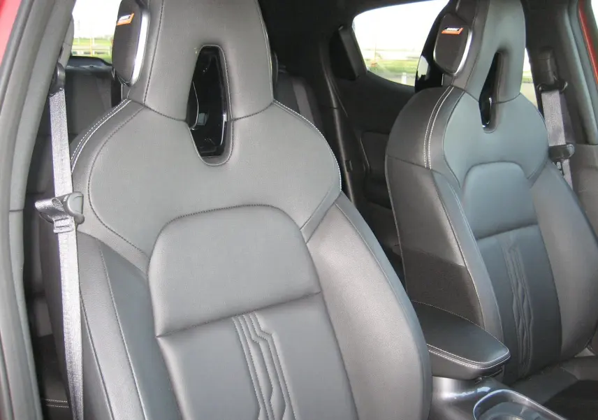 Vue intérieure rapprochée des sièges avant en cuir noir du Nissan Juke 1.6 Hybrid 143 Tekna rouge de 2024.