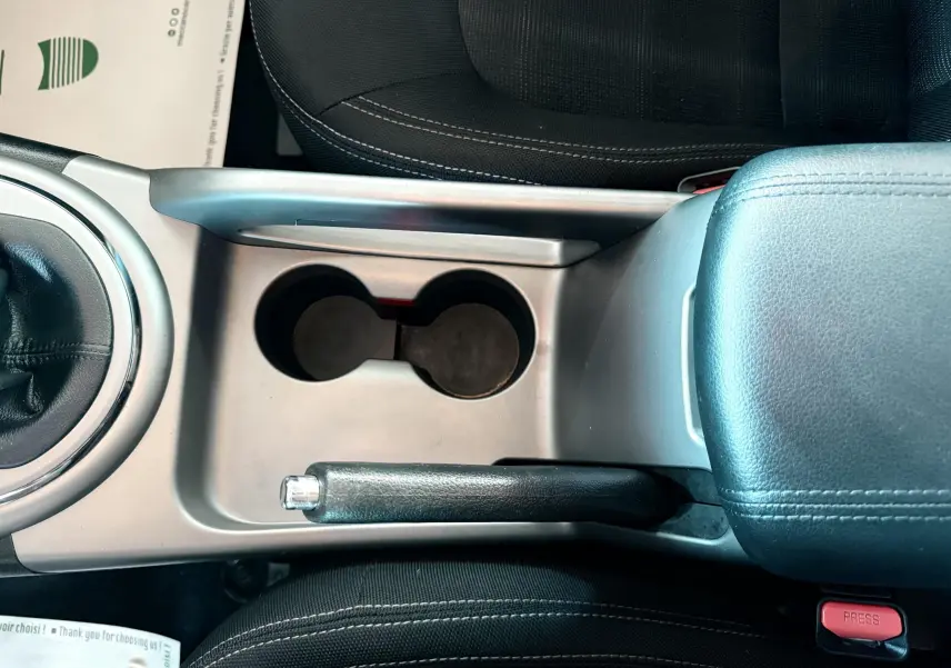 Vue plongeante sur la console centrale noire et grise avec frein à main et porte-gobelets du Kia Sportage blanc 2015