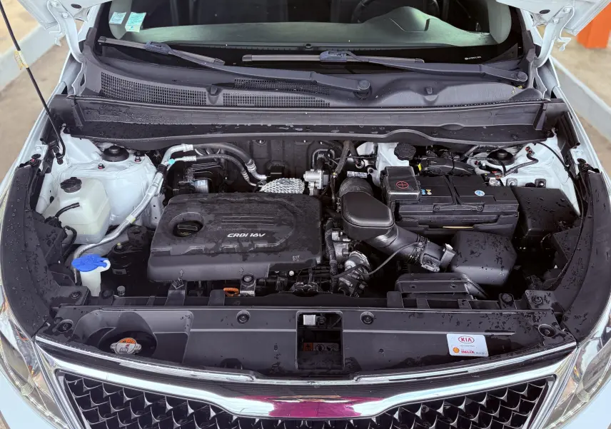 Vue plongeante sur le moteur CRDI 1.7 diesel d'un Kia Sportage blanc avec capot ouvert, montrant les composants sous le capot.