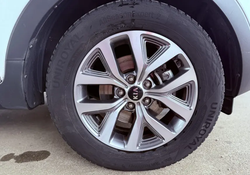 Gros plan sur la roue avant droite d'un KIA SPORTAGE blanche, mettant en valeur la jante alliage et le pneu Uniroyal.