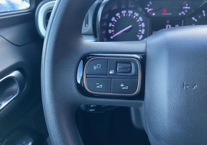 Gros plan sur les commandes audio au volant à gauche du tableau de bord de la Citroën C3 noire toit rouge 2023.