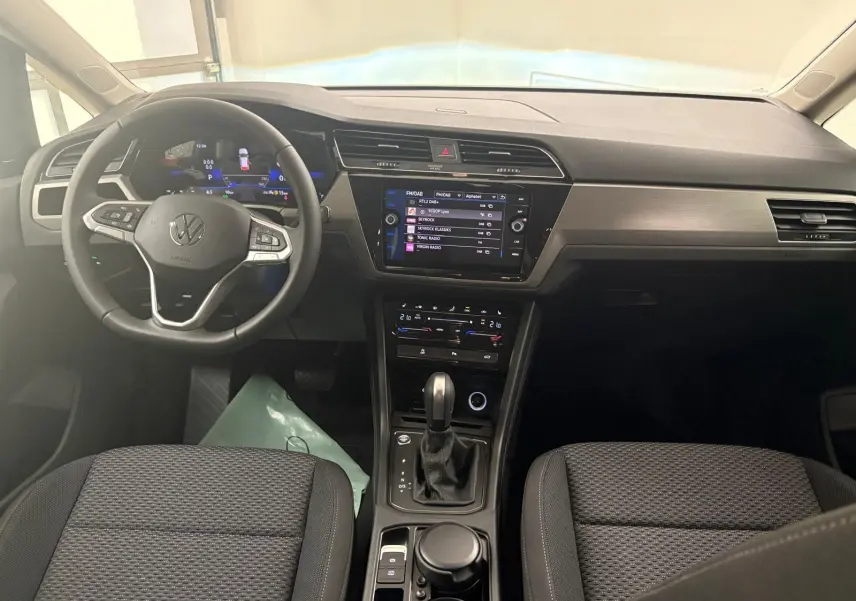 Vue intérieure du tableau de bord et volant du Volkswagen Touran 2025, finition VW Edition, avec écran tactile et sellerie noire.