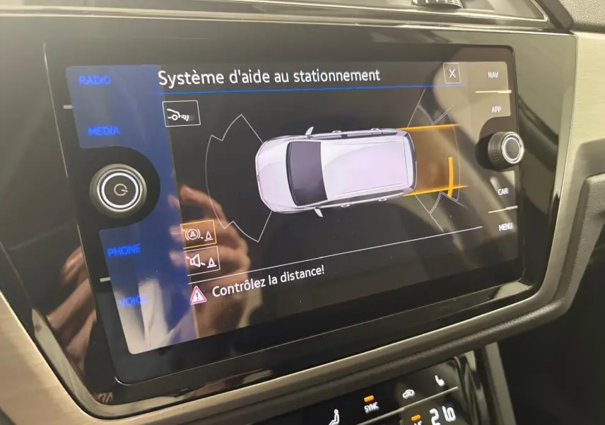 Écran tactile intérieur du Volkswagen Touran 2025 affichant le système d'aide au stationnement avec alertes de distance.