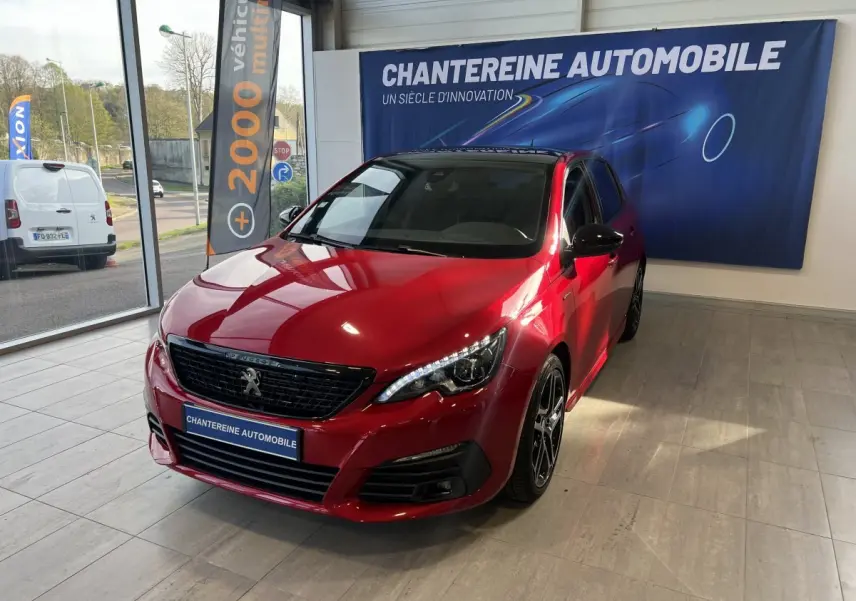 Peugeot 308 Puretech 130 S&S GT Line rouge vue en 3/4 avant droit dans un showroom avec jantes noires.