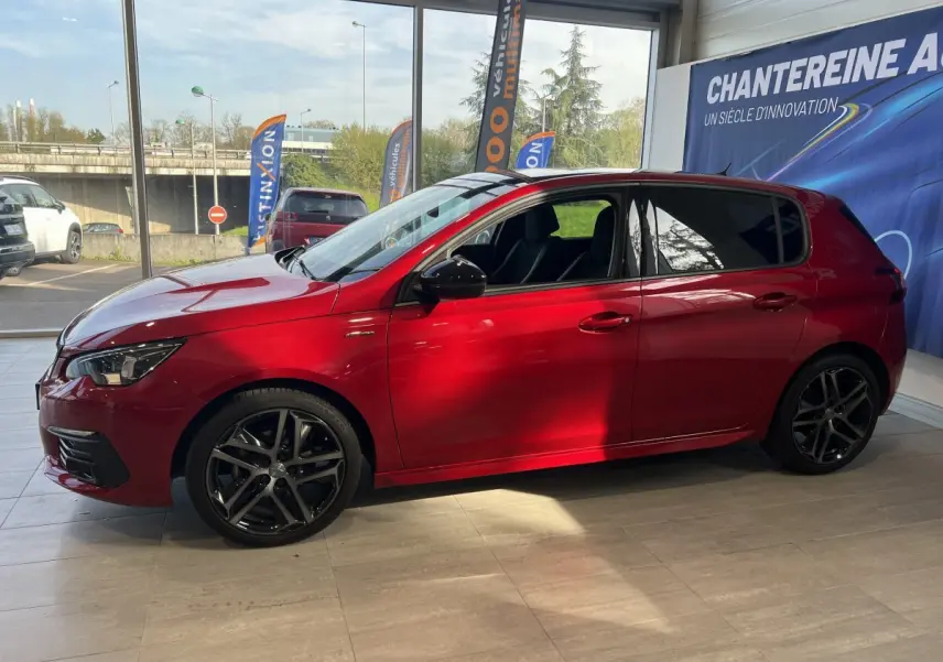 Peugeot 308 Puretech 130 S&S GT Line rouge vue de profil côté gauche en intérieur avec jantes alliage noires.