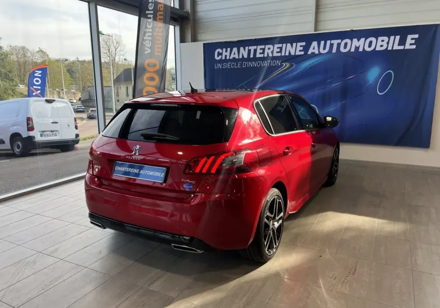 PEUGEOT 308 Puretech rouge vue 3/4 arrière droit en showroom avec feux arrière LED et jantes alliage noires.