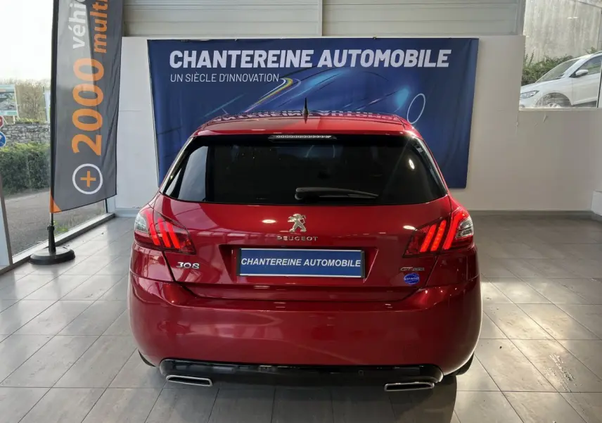 Vue arrière d'une Peugeot 308 Puretech 130 S&S GT Line rouge, avec feux LED et double sortie d'échappement chromée.