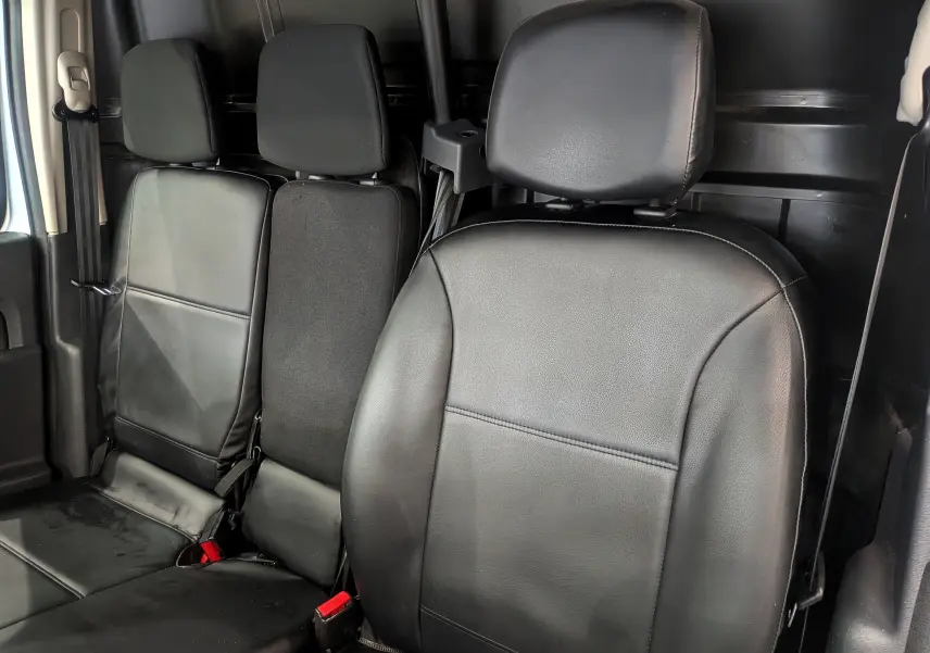 Vue intérieure des sièges avant et arrière noirs du Renault Kangoo Express gris Highland, version Blue dCi 2021.