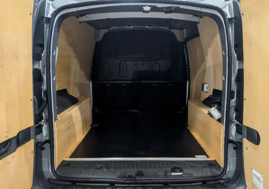 Vue arrière ouverte du Renault Kangoo Express gris Highland, montrant l'espace de chargement avec aménagements en bois.