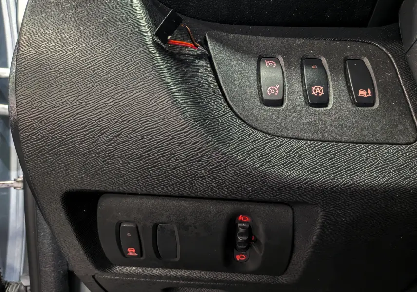 Gros plan sur les commandes de réglage des phares et aides à la conduite du Renault Kangoo Express gris Highland, version 2021.