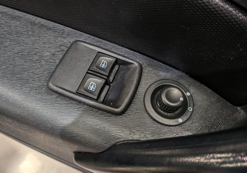Gros plan sur les commandes de lève-vitres et réglage des rétroviseurs côté conducteur du Renault Kangoo Express gris Highland 2021.