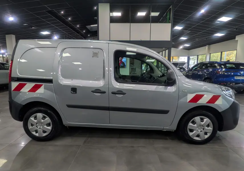 Profil gauche d'un Renault Kangoo Express gris Highland avec bandes réfléchissantes rouges et blanches sur les ailes avant et arrière.