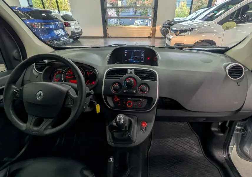 Vue intérieure du tableau de bord et volant du Renault Kangoo Express gris Highland, avec écran central et commande manuelle.