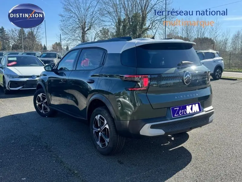 Vue 3/4 arrière droite d'un Citroën C3 Aircross 2026 vert Montana avec toit blanc Opale et jantes distinctives.