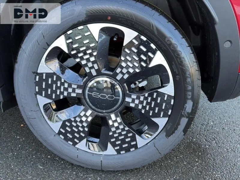 Gros plan sur la roue avant droite d'une FIAT 600 rouge, mettant en valeur la jante alu au design moderne.