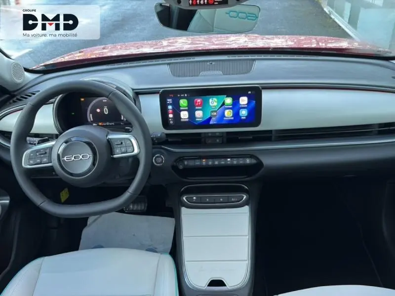 Vue intérieure avant de la FIAT 600 rouge 2026, tableau de bord moderne avec écran tactile et volant multifonction.