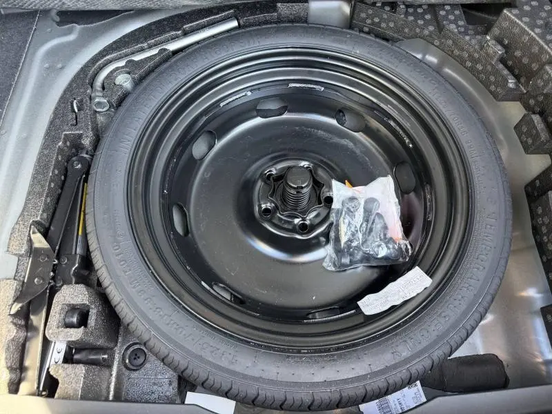 Roue de secours noire en acier dans le coffre d'une CUPRA Formentor 1.5 eTSI Hybrid 2025, entourée d'outils de bord.