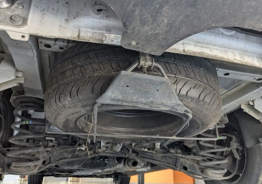 Vue en contre-plongée sous le FIAT Scudo Fourgon blanc, montrant la roue de secours suspendue et la suspension arrière.