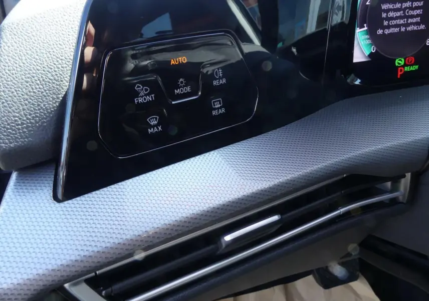 Détail du tableau de bord gris clair de la Volkswagen Golf 2024 avec commandes d’éclairage et ventilation intégrées.