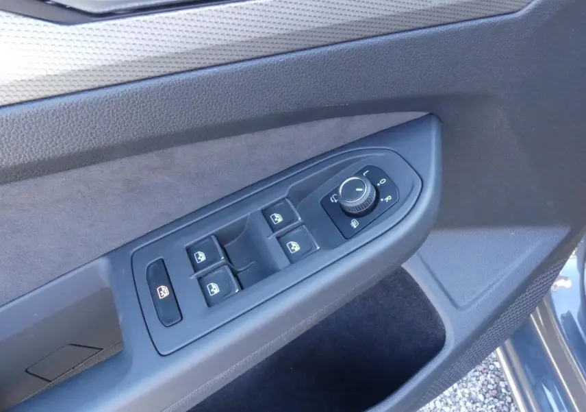Commande des vitres et réglage des rétroviseurs sur la porte côté conducteur d'une Volkswagen Golf gris métallisé 2024