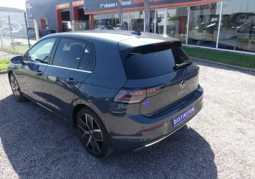 Vue 3/4 arrière droite d'une Volkswagen Golf 1.5 eTSI Style 2024 gris métallisé avec jantes alliage et vitres surteintées.