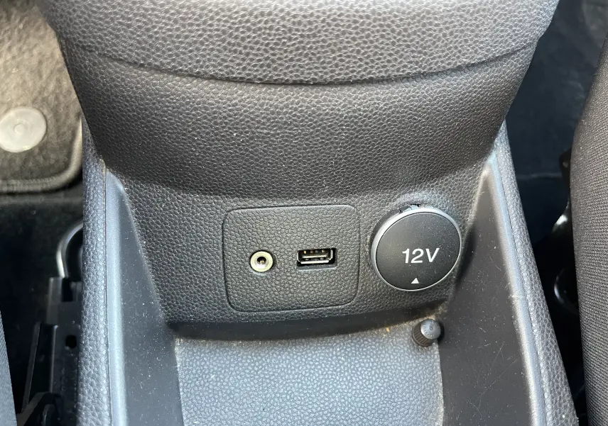 Prise USB, prise jack et prise 12V intégrées dans la console centrale noire d'une Ford Fiesta gris titane 2014.