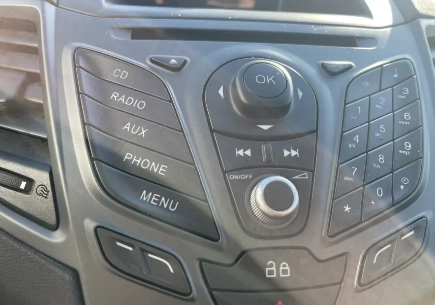 Gros plan sur la console centrale noire de la Ford Fiesta 2014 gris titane, montrant les boutons radio, téléphone et menu.