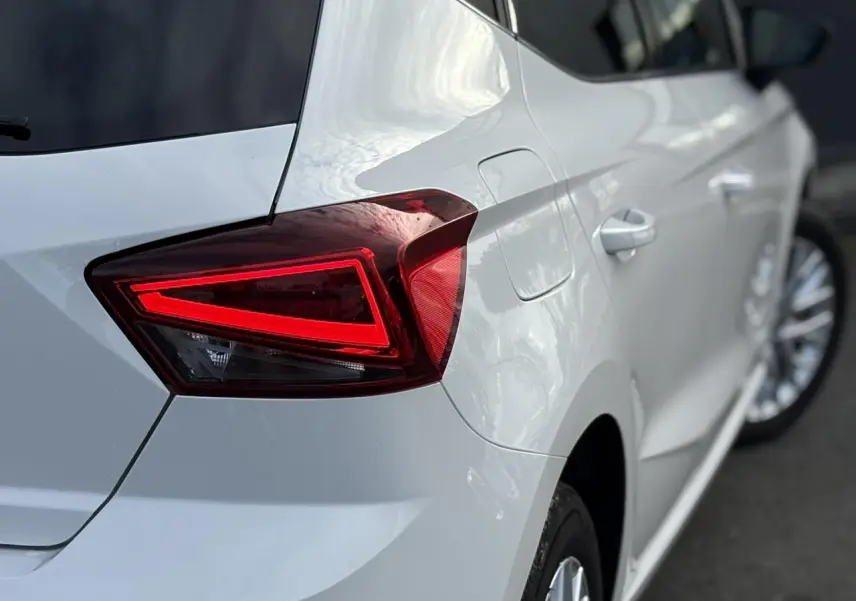 Gros plan sur le feu arrière droit rouge d'une SEAT Ibiza blanche, avec partie latérale et jante visible.