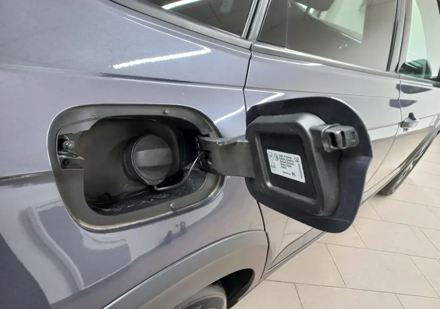 Gros plan sur la trappe à carburant ouverte côté gauche d’un Volkswagen Taigo gris cendré, vue latérale.