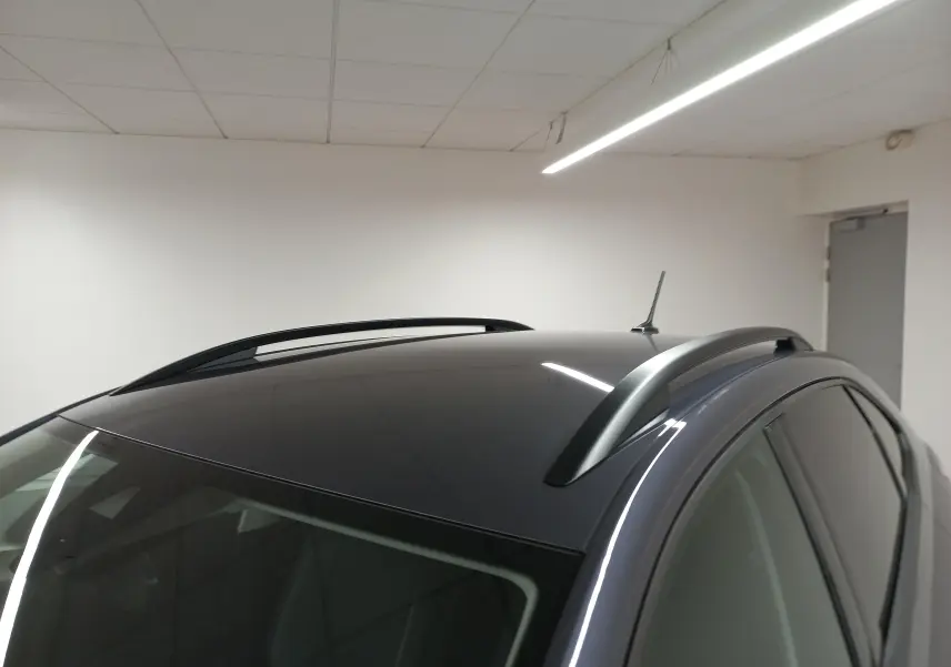 Vue rapprochée du toit gris cendré du Volkswagen Taigo 2025 avec barres de toit et antenne, en intérieur.