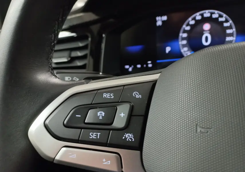 Gros plan sur les commandes du volant du Volkswagen Taigo 2025, boutons de régulateur de vitesse et assistance conduite visibles.