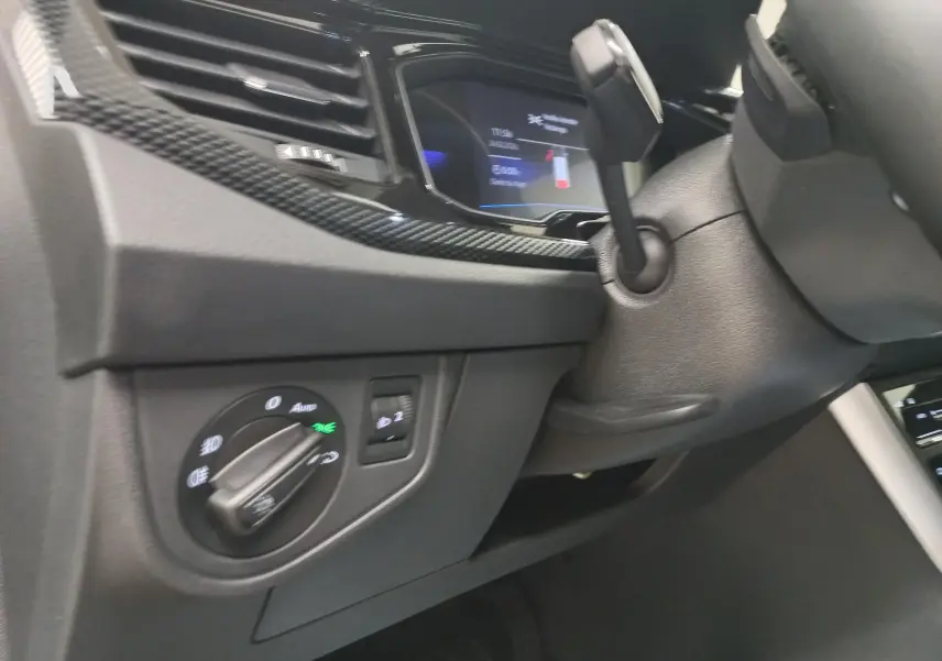 Détail intérieur du tableau de bord côté gauche du Volkswagen Taigo 2025 avec commandes d’éclairage et finition noire.