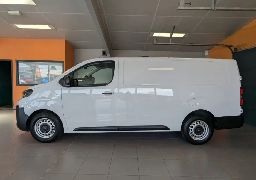 Vue de profil côté gauche du fourgon FIAT Scudo XL blanc avec jantes tôles grises 17 pouces en intérieur showroom.