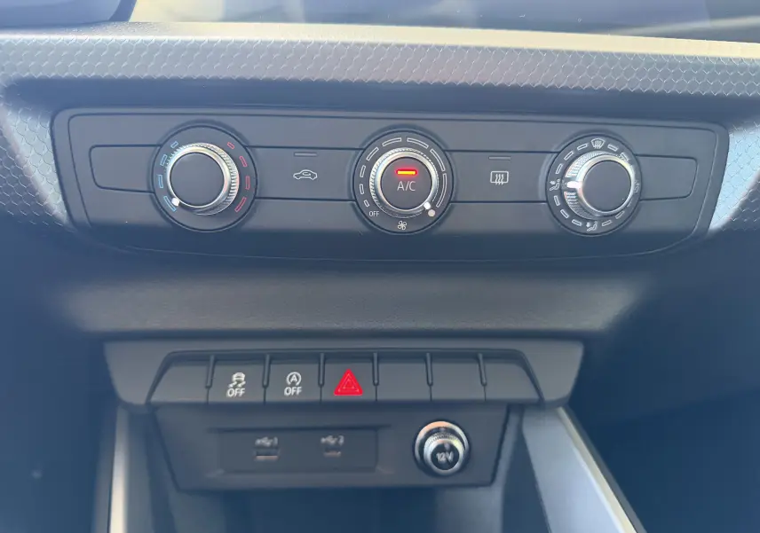 Vue rapprochée de la console centrale de l'Audi A1 Sportback 2020, montrant les commandes de climatisation et boutons de sécurité.