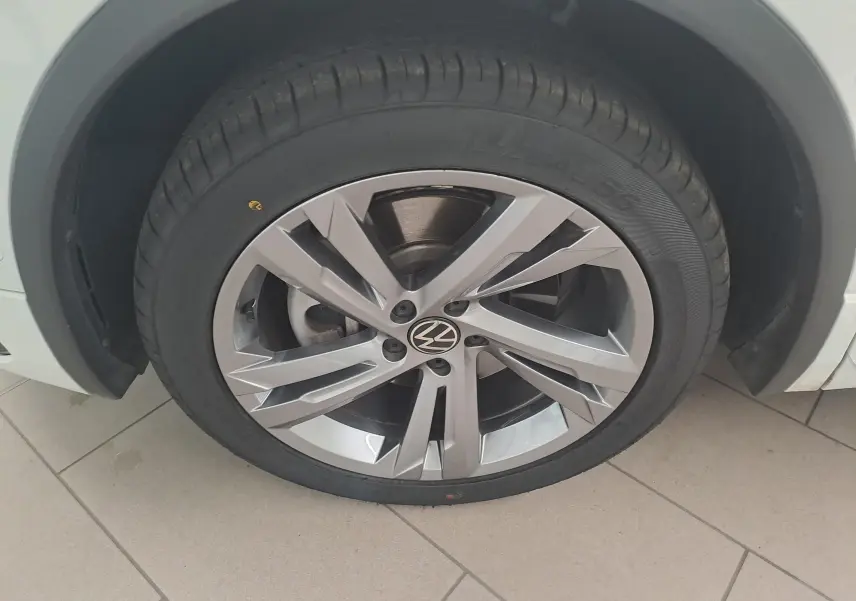 Gros plan sur la roue avant gauche du Volkswagen Tiguan blanc pur 1.4 eHybrid 245 DSG6 R-LINE avec jante alliage distinctive.