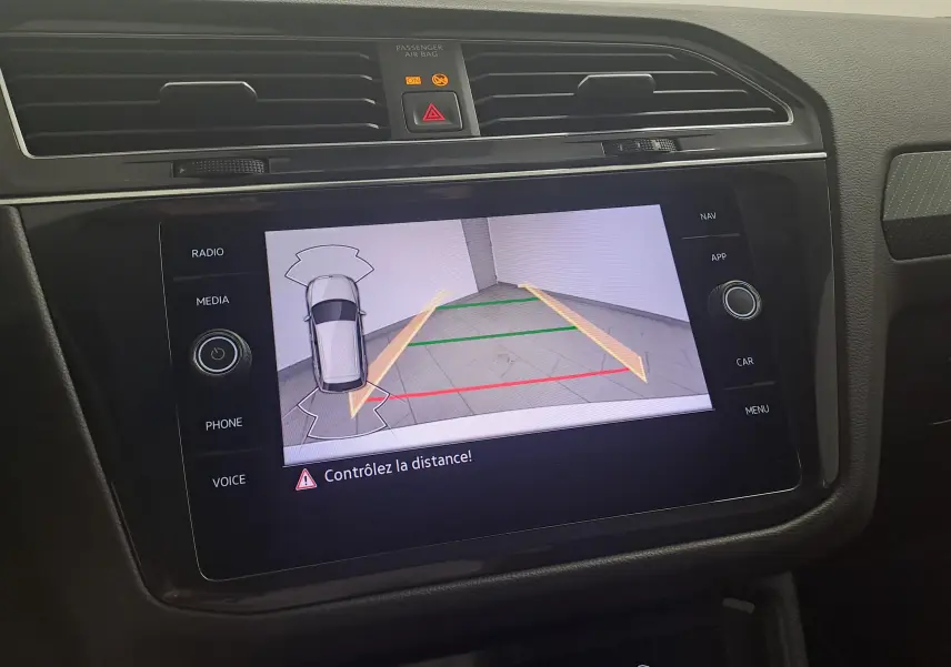Écran central du Volkswagen Tiguan 2023 blanc pur montrant la caméra de recul avec guidage dynamique.