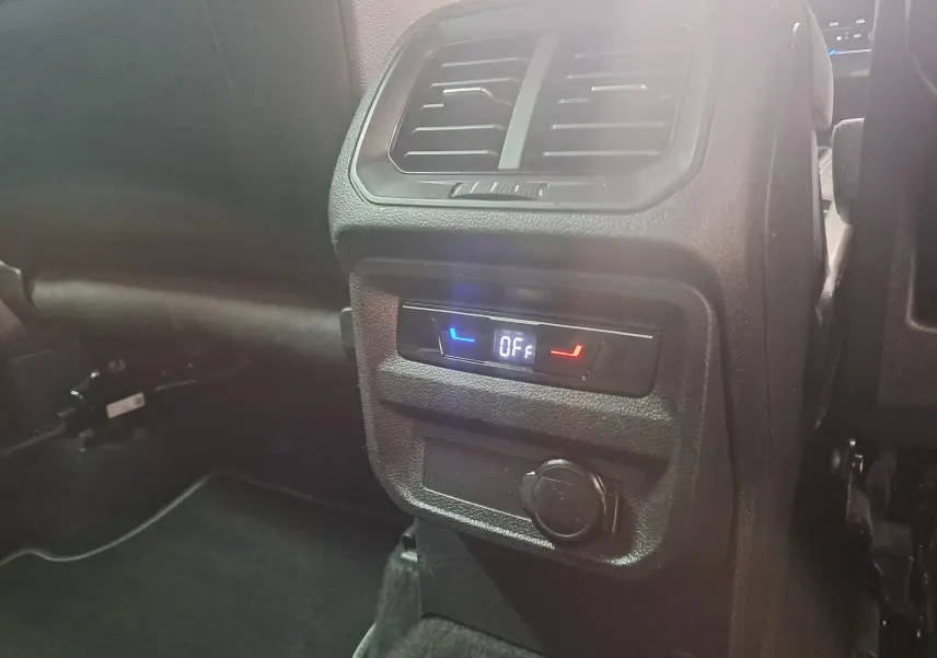 Détail de la console arrière noire du Volkswagen Tiguan 1.4 eHybrid 2023 avec commandes climatisation et prise 12V.