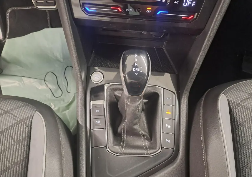 Vue rapprochée de la console centrale du Volkswagen Tiguan blanc pur 2023, avec levier de vitesse automatique et boutons de mode hybride.
